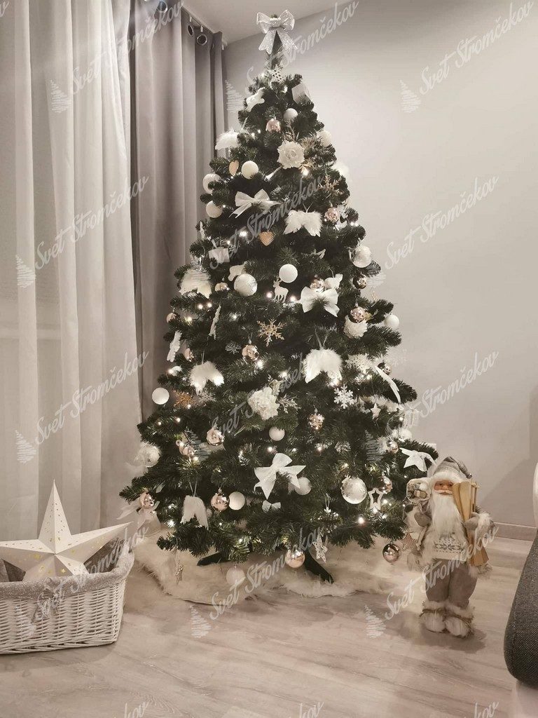Zelený vianočný stromček ozdobený bielými guľami a anjelskými krídlami .