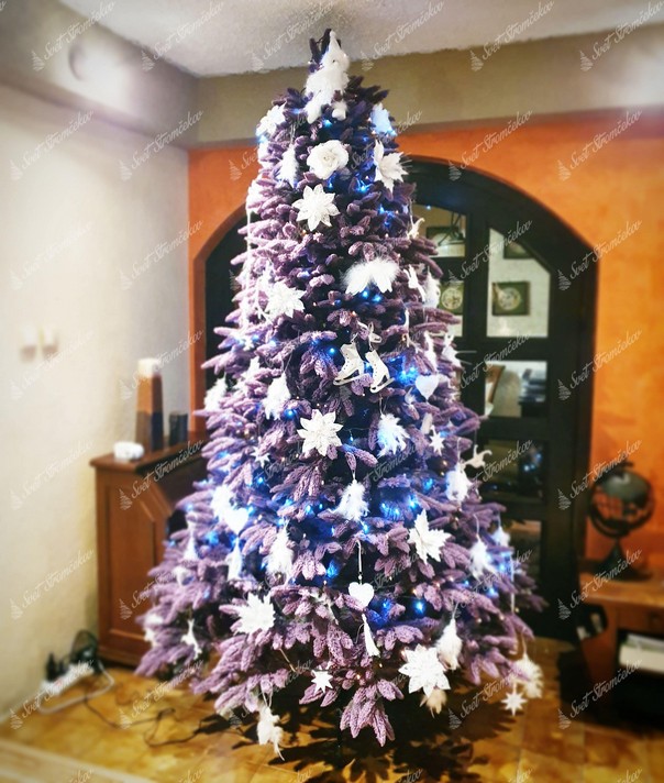 Fialový vianočný stromček ozdobený bielými kvetmi a vianočnými ozdobami