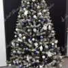 Vianočný stromček s jemne zasneženými končekmi vetvičiek ozdobený bielými a modrými vianočnými ozdobami .
