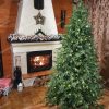 Svietiaci vianočný stromček 3D Smrek Horský pri rozhorenom krbe. Celá miestnosť je vianočne ozdobená.