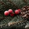 Detail vianočného venčeka pokrytého bielymi chumáčikmi, borovicovými šiškami a červenými lesnými plodmi.
