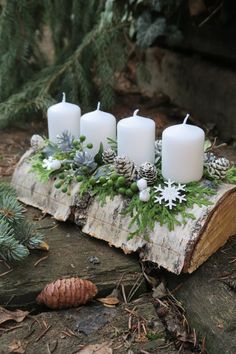 Adventný veniec na dreve. Biele sviečky na podlhovastom kmeni stromu, dozdobenom čečinou.