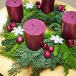 Fialový adventný veniec na čečine. Okrúhle veniec je dozdobený fialovými ozdobami a sviečkami.