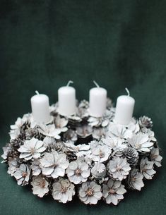 Strieborný adventný veniec zo strieborných kvetov na ktorom sú štyri biele adventné sviečky.