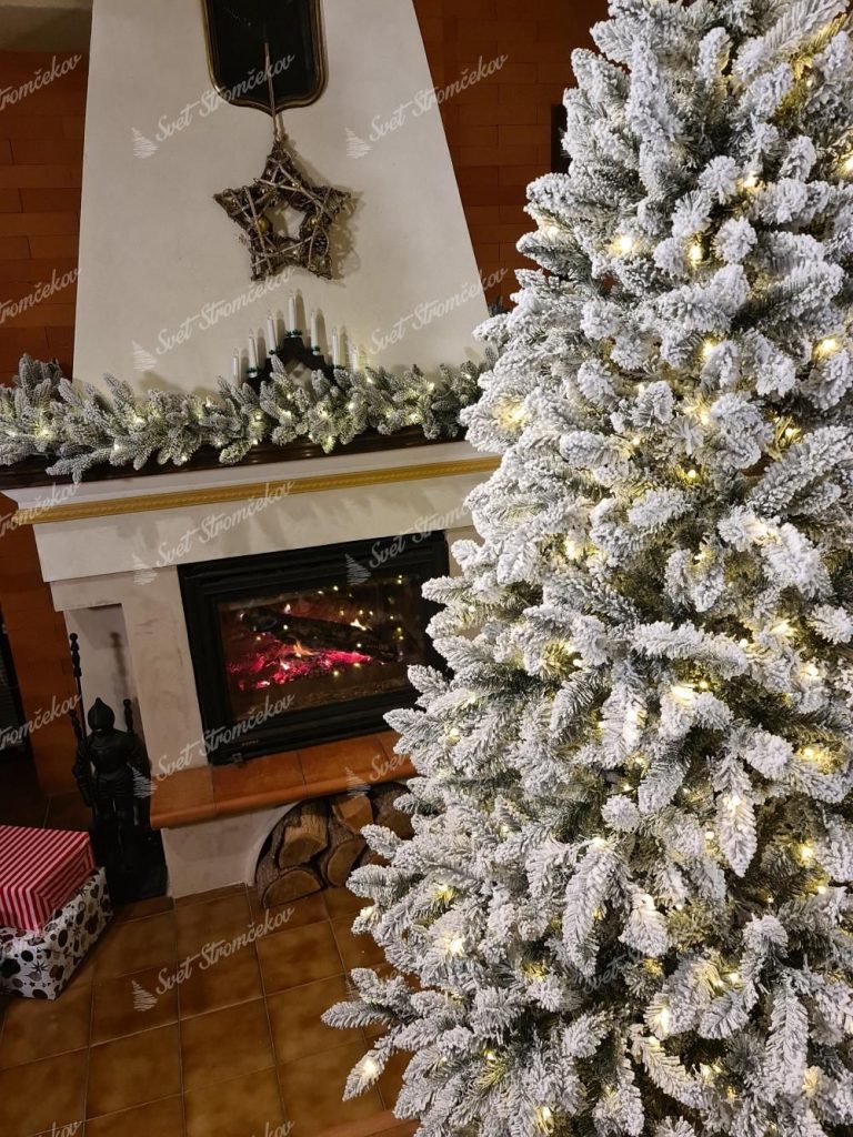 Vianočný stromček Smrek Severský LED. Detail bieleho vianočného stromčeka so svetielkami pri krbe.