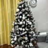 Umelý vianočný stromček s tmavými vetvičkami, ozdobený bielymi vetvičkami, s bielym kobercom pod stromček