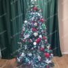 Umelý vianočný stromček s tmavozelenými vetvičkami, ozdobený červeno-zelenými ozdobami.