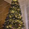 Vysoký umelý vianočný stromček s tmavozelenými vetvičkami, ozdobený fialovo-striebornými ozdobami