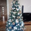 Zelený umelý vianočný stromček, ozdobený bielo-zlatými ozdobami.