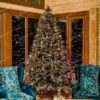 Vysoký a široký umelý vianočný stromček, s bledozelenými hustými vetvičkami, ozdobený fialovými ozdobami