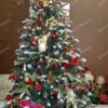 Umelý vianočný stromček so zasneženými koncami vetvičiek, s dekoráciou šišiek, ozdobený červeno-zlatými ozdobami