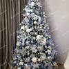 Umelý vianočný stromček so zasneženými vetvičkami,husto ozdobený strieborno-modrými ozdobami
