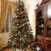 Umelý vianočný stromček s tmavými zelenými vetvičkami, ozdobený zlato-červenými ozdobami, v obývačke.