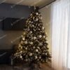Široký umelý vianočný stromček, ozdobený bielo-zlatými ozdobami a teplým osvetlením.