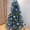 Umelý vianočný stromček so zeleno-striebornými vetvičkami, s bielo-strieborno-zelenou vianočnou výzdobou.