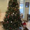 Vysoký a mohutný umelý vianočný stromček v obývačke, ozdobený červeno-zlatými ozdobami.