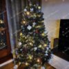 Klasický umelý vianočný stromček so striebornými koncami vetvičiek, ozdobený bielým a červenými vianočnými ozdobami s teplým bielym osvetlením.
