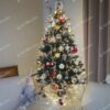 Nízky umelý vianočný stromček so striebornými koncami vetvičiek a drobnými kryštálikmi ľadu, s červeno-bielymi ozdobami a jemným vianočným osvetlením.