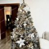 Umelý zasnežený vianočný stromček ozdobený bielymi a zlatými ozdobami.