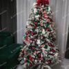 Umelý vianočný stromček so zasneženými vetvičkami, s červenými ozdobami.