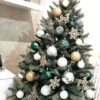 Umelý vianočný stromček so strieborno-zlatými a smaragdovými ozdobami.