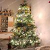Vianočný stromček so zeleným ihličím, s drevenými ozdobami, s teplým bielym osvetlením, v obývačke.