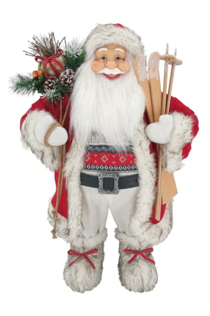 Dekorácia Santa Claus červeno biely 80cm má oblečený červený kabátik so hnedobielym lemovaním, pod ním má sveter s vianočným vzorom. Na nohách má obuté kožušinové topánky. V rukách drží lyže a na pleci má batoh s čečinou a šiškami