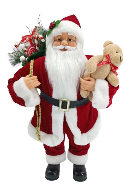 Dekorácia Santa Claus tradičný 60cm má oblečený červený kabátik s bielym lemom. Opásaný je čiernym opaskom so zlatou ozdobou. Na nohách má obuté čierne topánky. v ruke drži plyšového macka a na pleci má zavesený batoh s čečinou a darčekmi.