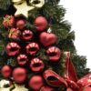 Malý zelený vianočný stromček so zlatými a červenými vianočnými guľami a červeno-zlatou mašľou.