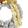 Zasnežený vianočný veniec na dvere so zlatými ozdobami, šiškami, škoricou a zlatou mašľou