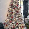 Umelý vianočný stromček Smrek Severský 210cm, stromček je husto zasnežený a ozdobený bielymi a červenými ozdobami